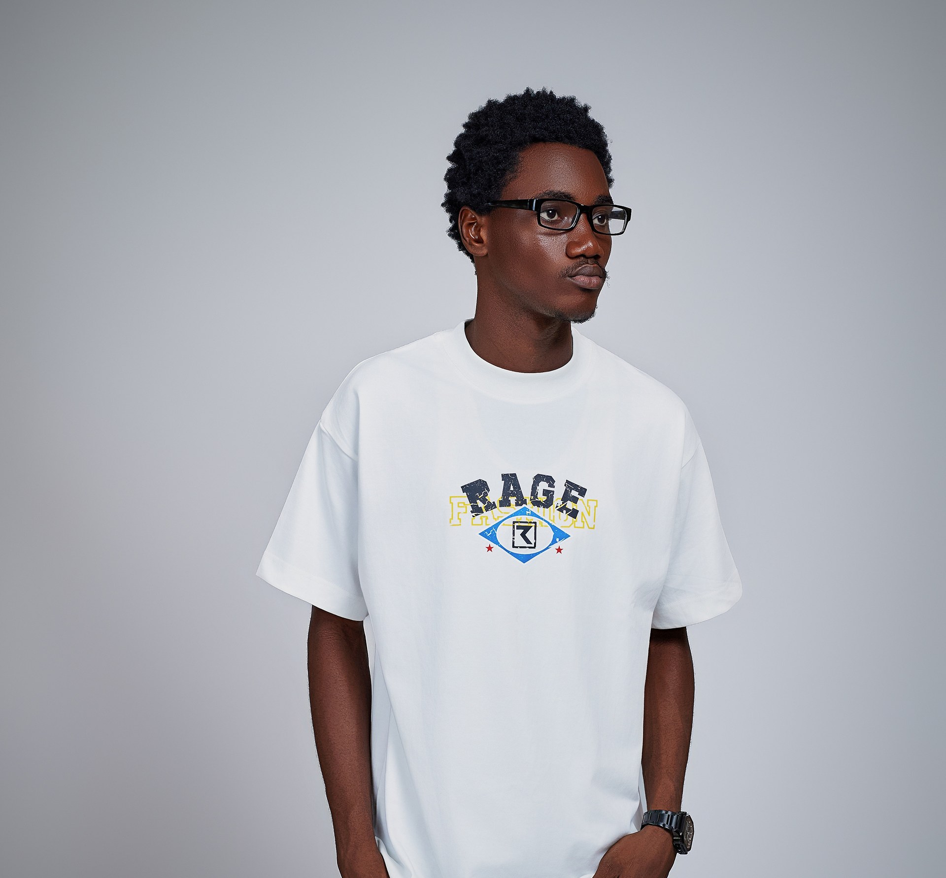 Kanann in a white Rage tee looking to the side against a grey backdrop
