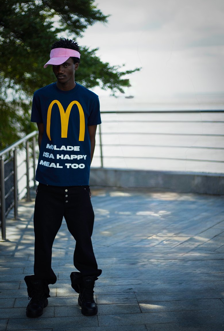 Kanann in a pink visor and navy tee on a seaside terrace