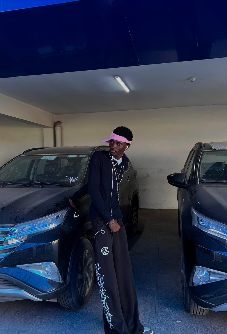 Kanann in a pink visor standing between two parked cars in a garage