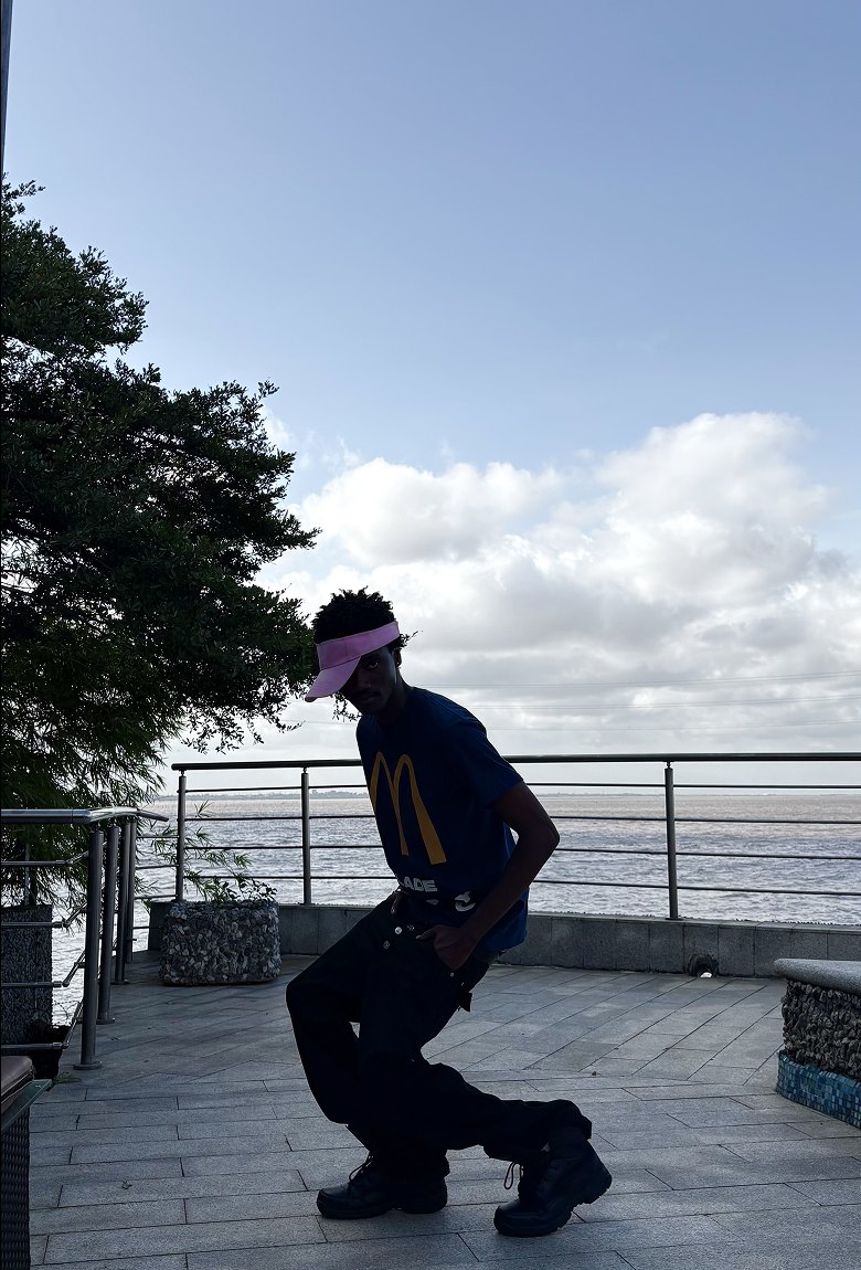 Silhouette of Kanann crouching against the sky at a terrace railing