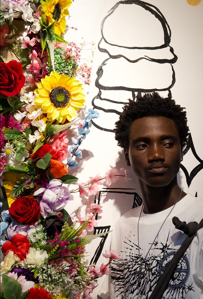 Close-up of Kanann in front of a flower wall
