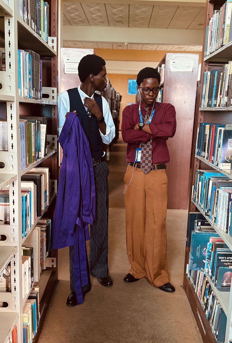 Two men talking between library shelves